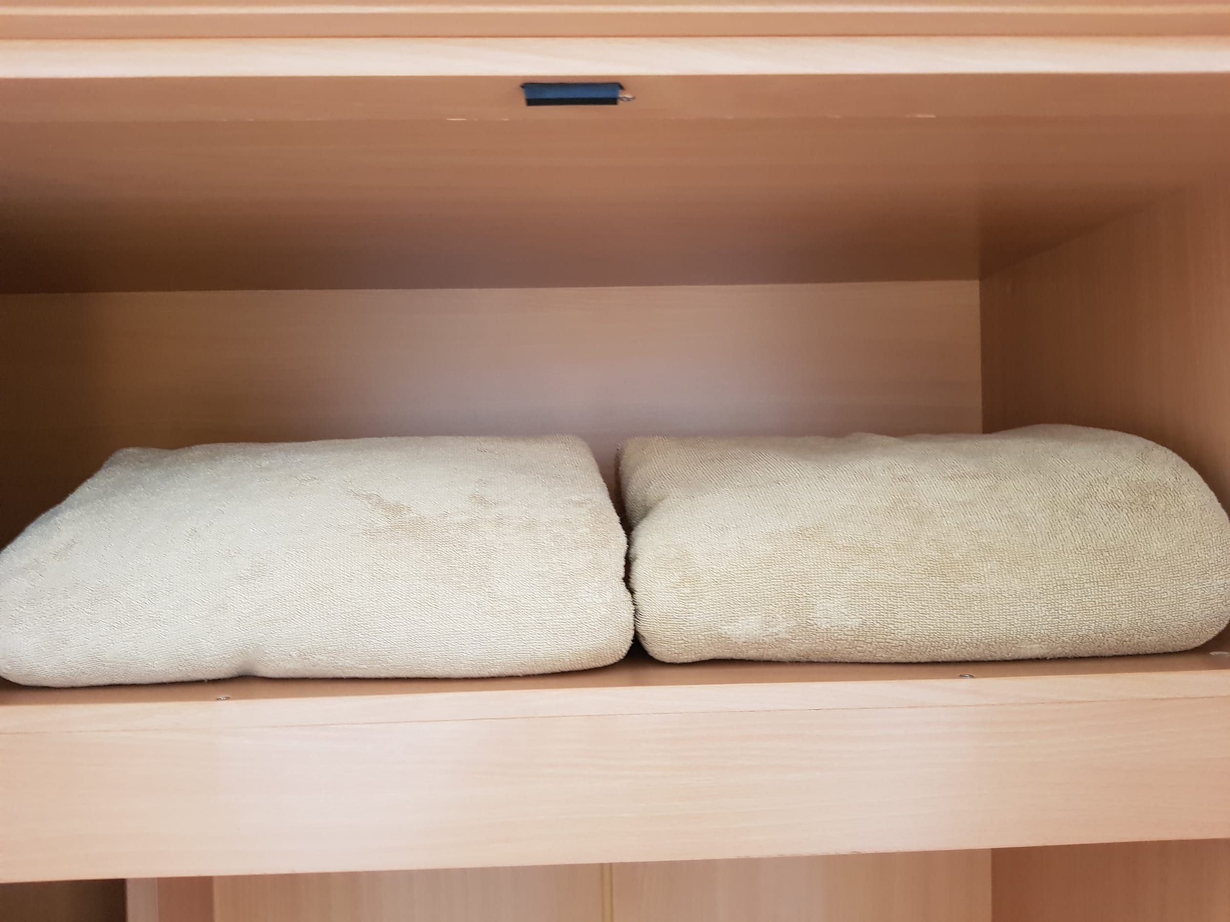 Zwei gefaltete beige Frotteedecken auf einem Regalboden im Schrank