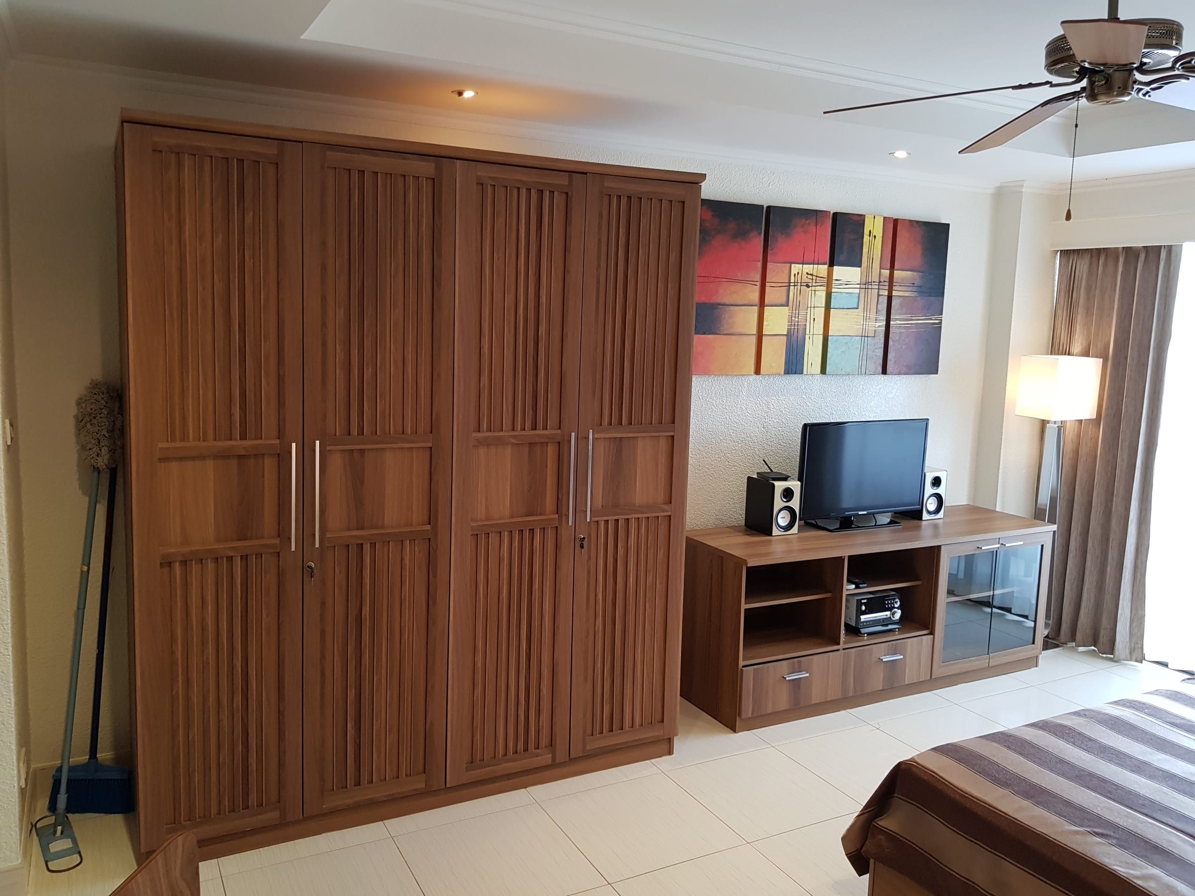 Studio Typ B: dunkler Holzkleiderschrank und Flachbild-TV auf dem Sideboard