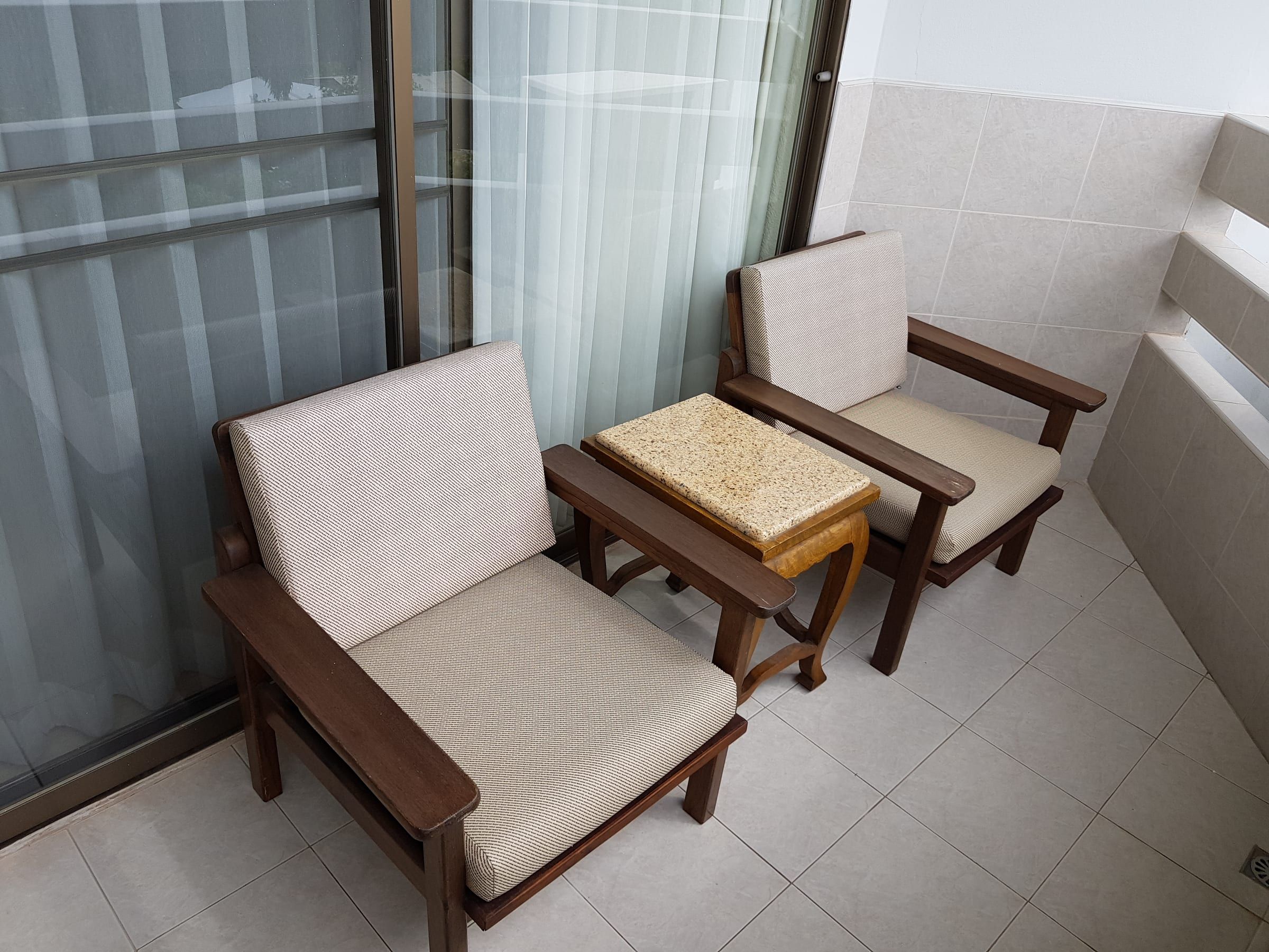 Gefliester Balkon mit zwei gepolsterten Holzstühlen und kleinem Tisch