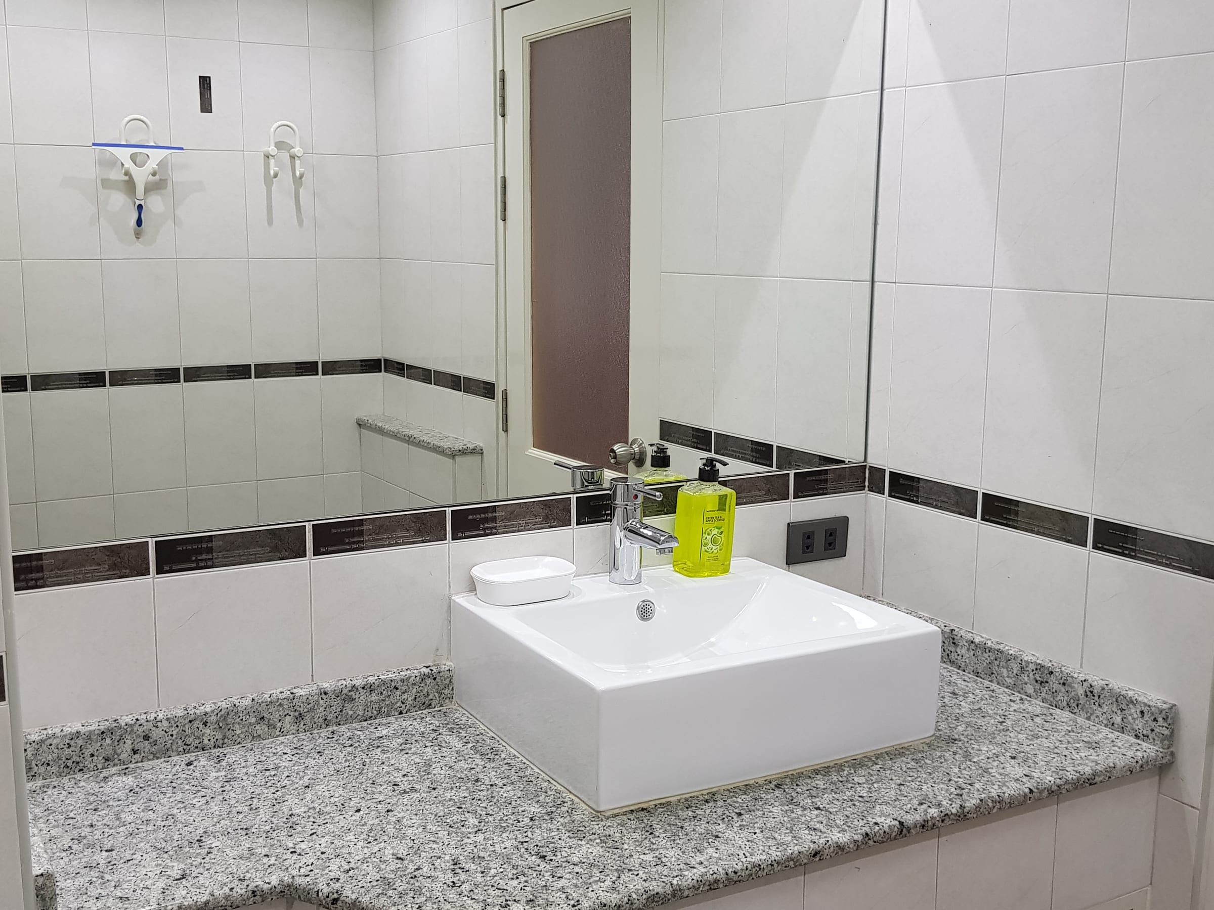 Badezimmer Typ B: weißes Waschbecken auf Granitplatte mit Spiegel und Ablage