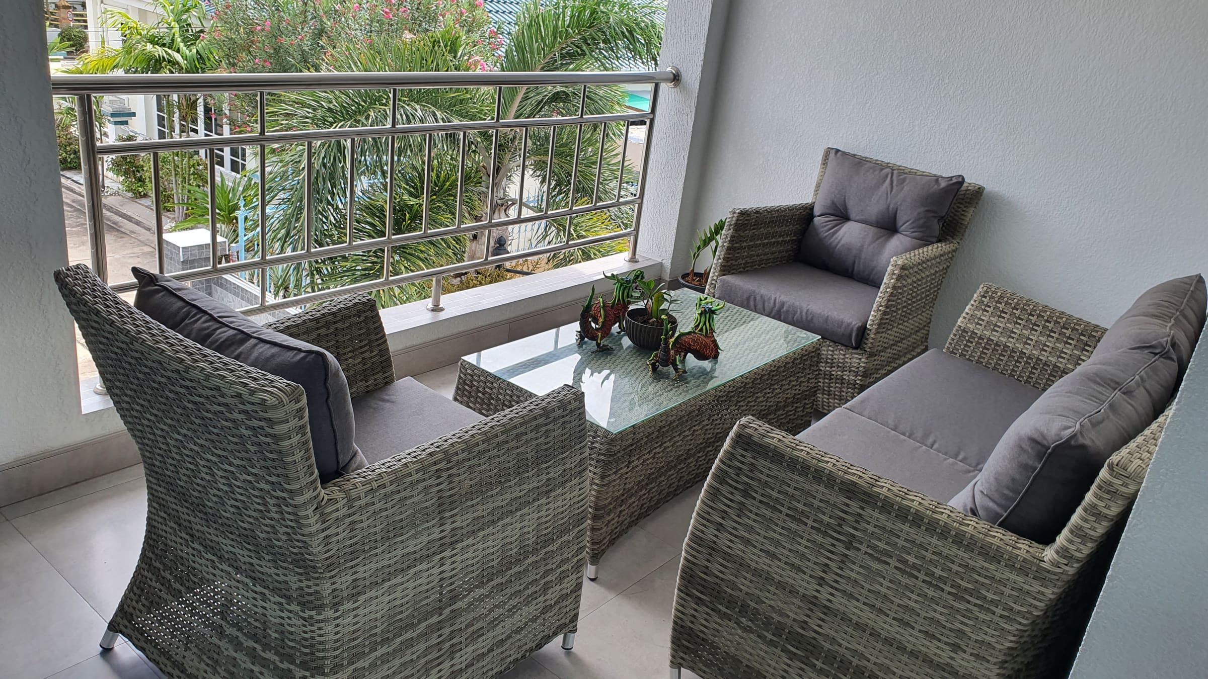 Terrasse avec salon de jardin en rotin gris et vue sur les palmiers