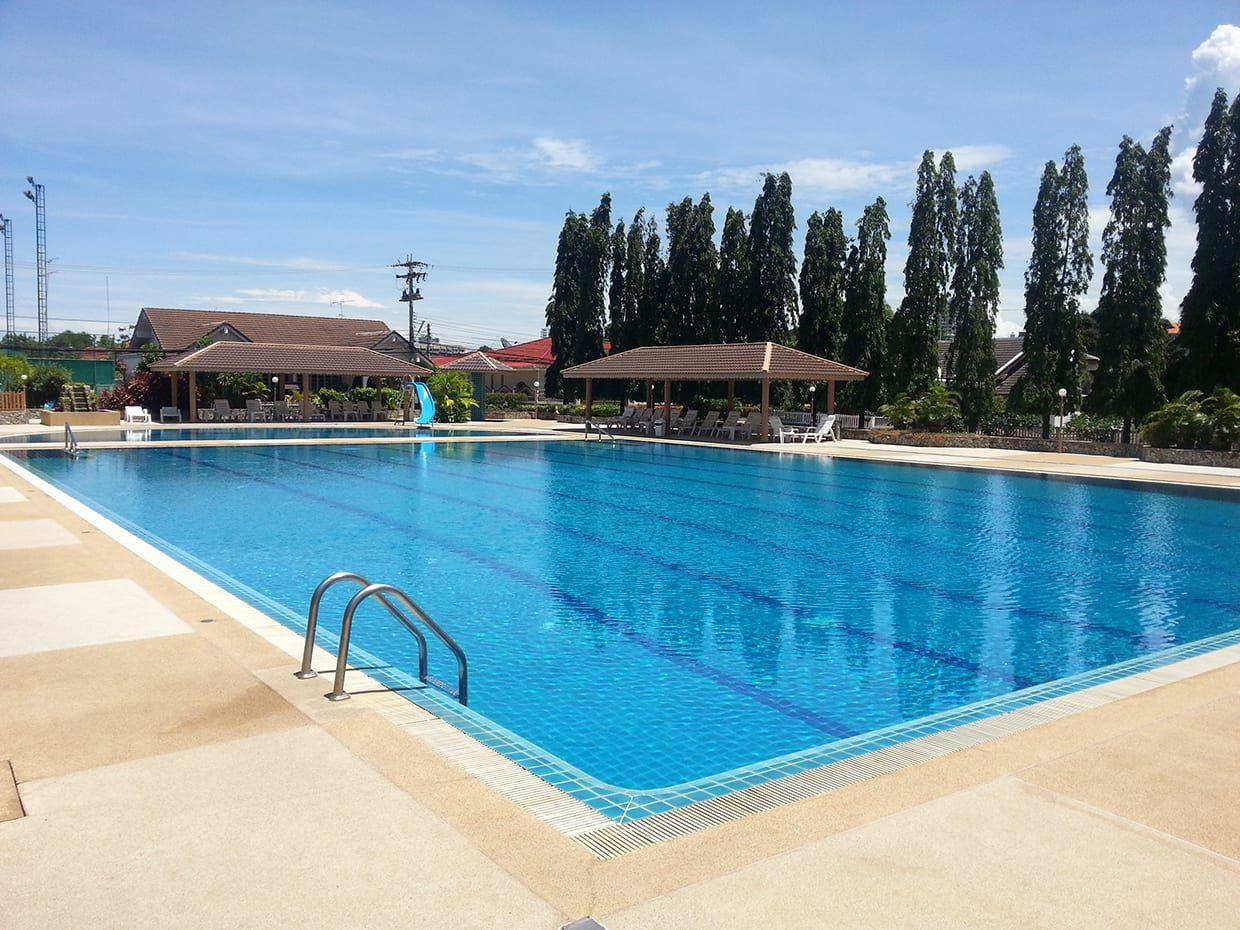 Blick über den Pool auf den Pavillon des Pool-Restaurants und die hohen Bäume der Anlage